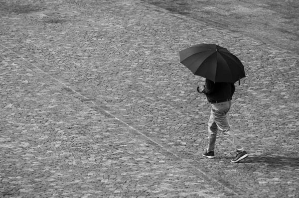 Man walking on cobblestone place with umbrella — Stock Photo, Image
