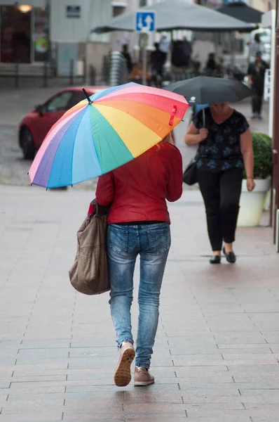 Mulher andando na rua com guarda-chuva arco-íris — Fotografia de Stock