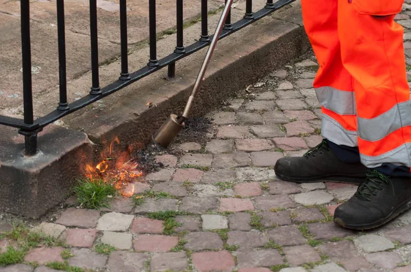Primer plano del trabajador quemando hierba en el pavimento en la calle — Foto de Stock