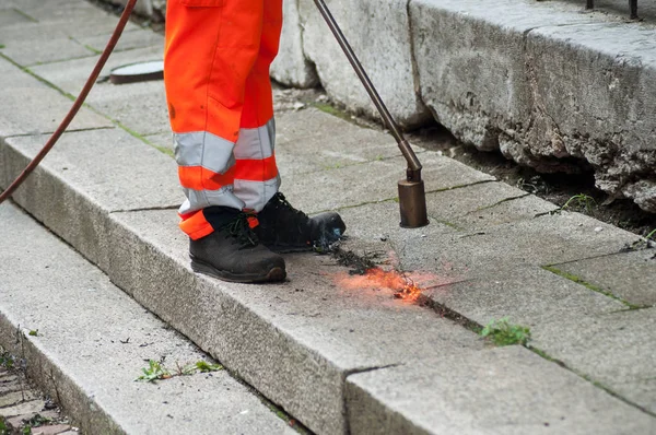 Primer plano del trabajador quemando hierba en el pavimento en la calle — Foto de Stock