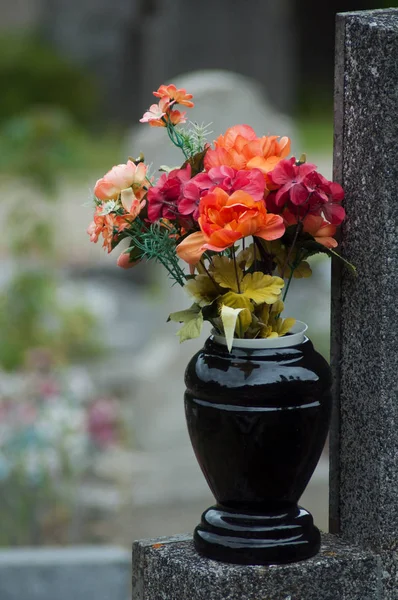 Närbild av konstgjorda blommor bukett i potten på graven i kyrkogården — Stockfoto