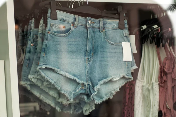 Close-up de jeans rasgado curto em cabides em uma loja de moda — Fotografia de Stock