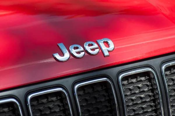 Primo piano del logo sul fronte jeep rosso parcheggiato in strada — Foto Stock