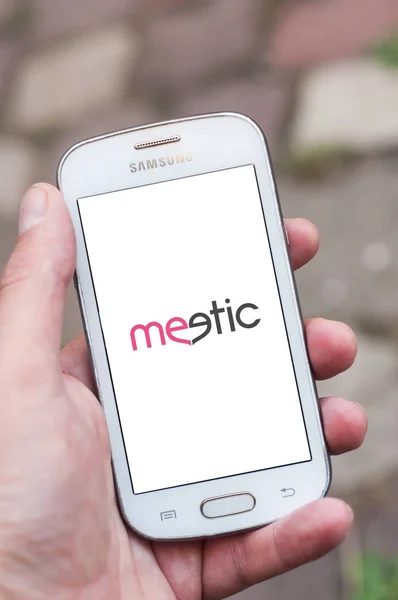 Fechar o logotipo Meetic na tela do smartphone na mão da marca Samsung na rua — Fotografia de Stock