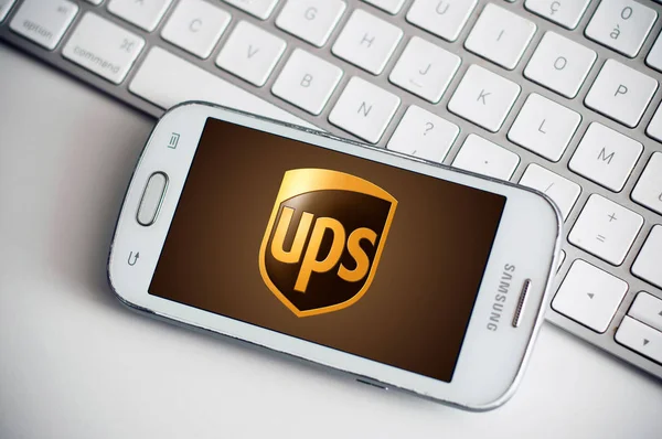 Ups logotipo na tela do smartphone da marca Samsung no fundo do teclado branco — Fotografia de Stock