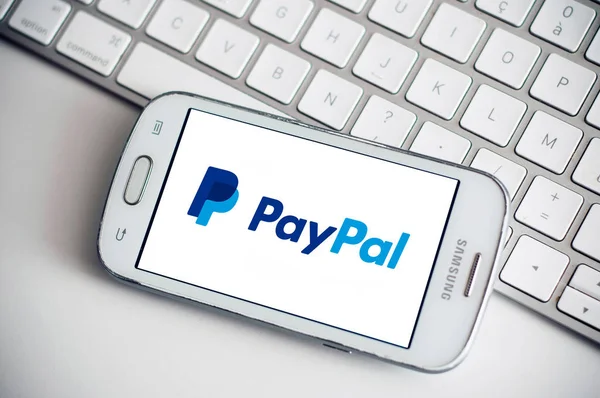 Logo PayPal na obrazovce smartphone od značky Samsung na bílém pozadí klávesnice — Stock fotografie