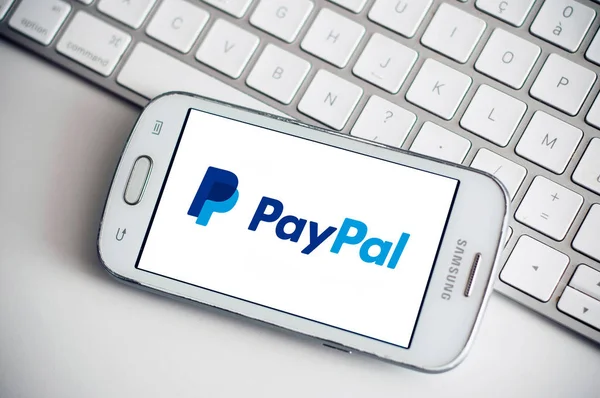 stock image Paypal logo on smartphone screen from Samsung brand on white keyboard background