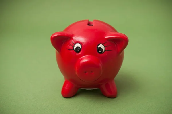 Closeup of red piggy bank on green background