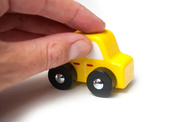Крупный план миниатюрного деревянного автомобиля в руке на белом фоне — стоковое фото