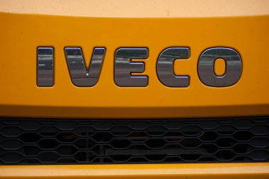  Sokakta park edilmiş turuncu kamyon önünde Iveco logosu closeup 