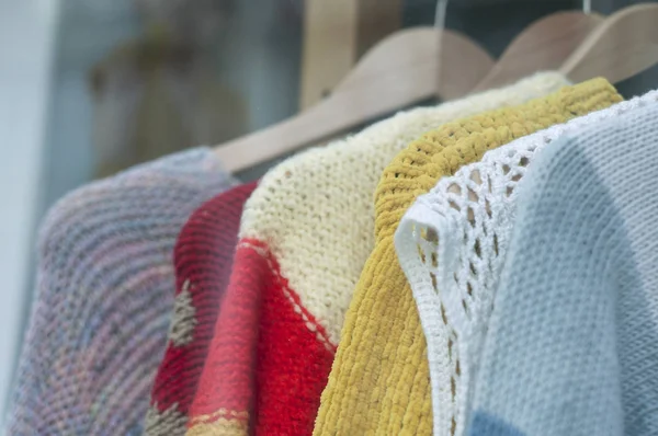 Крупный план красочной шерстяной пуловер на вешалках в женском магазине моды — стоковое фото