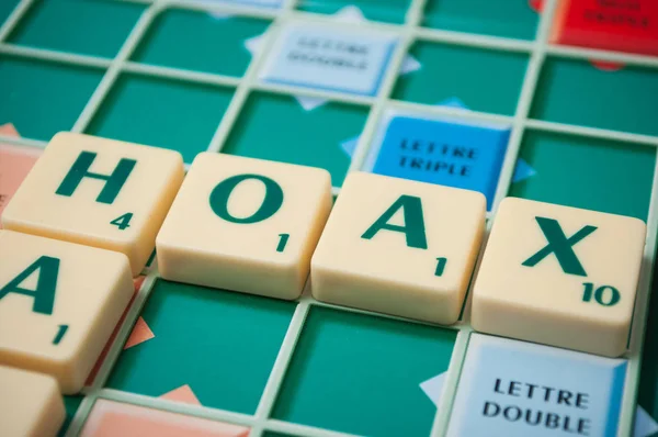 Plastic letters on Scrabble board game forming the word : Hoax — ストック写真
