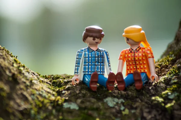 Персонажи PLaymobil сидят на стволе дерева на открытом воздухе — стоковое фото