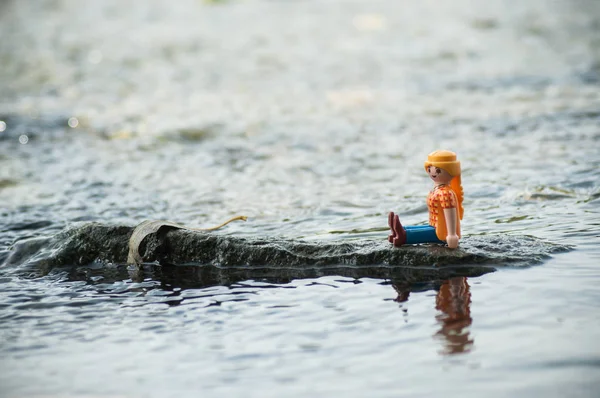 Personaje de PLaymobil en el rock en medio del río en el aire libre — Foto de Stock