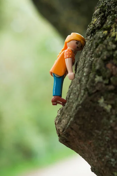 Персонажи Playmobil забираются на ствол дерева на открытом воздухе — стоковое фото