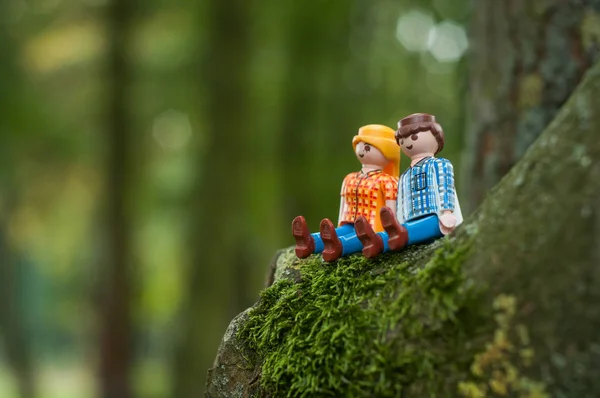 Персонажи PLaymobil сидят на стволе дерева на открытом воздухе — стоковое фото