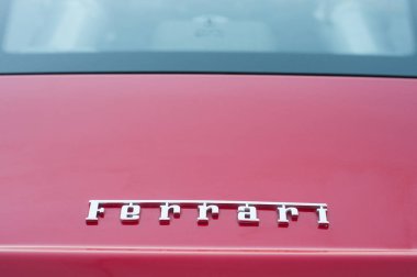 Kırmızı spor arabanın arkasında Ferrari logosu sokağa park edilmiş.