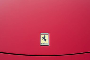 Ferrari logosu caddeye park etmiş kırmızı spor araba.