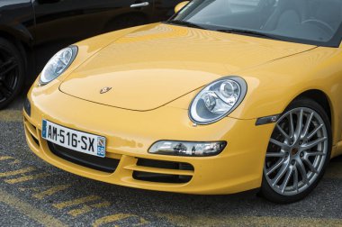 Sarı Porsche 911 'in önü sokağa park edilmiş.