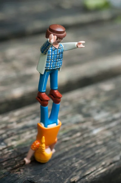 Фигуры Playmobil, стоящие в равновесии на деревянном столе на открытом воздухе — стоковое фото