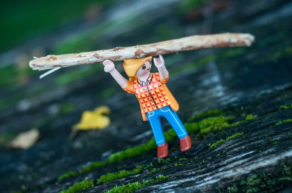 Фигура Playmobil, несущая ствол дерева над головой на деревянном полу — стоковое фото