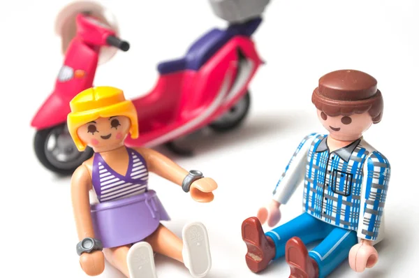 白い背景に赤いスクーターの近くに座っているPlaymobil人形 — ストック写真