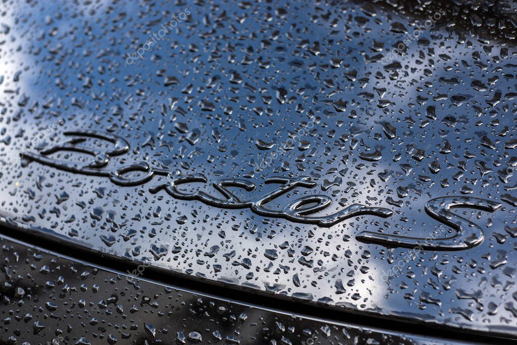 Mulhouse - France - 28 June 2020 - Closeup of rain drops on logo of black Porsche 718 boxster parked in the street