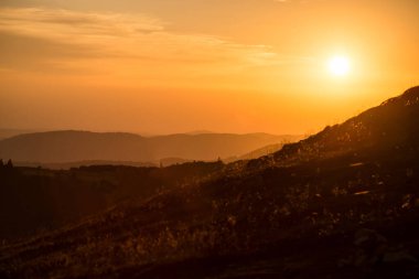 Gün batımını işaret fişeği olmadan dağların ön planında görmek