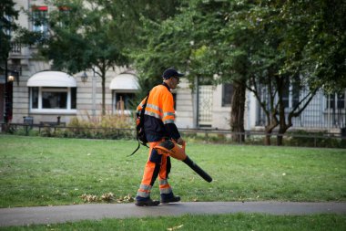 Mulhouse - Fransa - 23 Ağustos 2020 - Belediye bahçıvanı portresi kamu bahçesinde yolu temizlemek için yaprak üfleyici kullanıyor