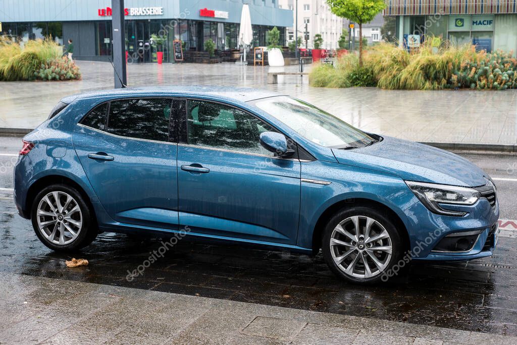 Mulhouse - France - 30 August 2020 - Profile view of blue Renault megane parked in the street by rainy day
