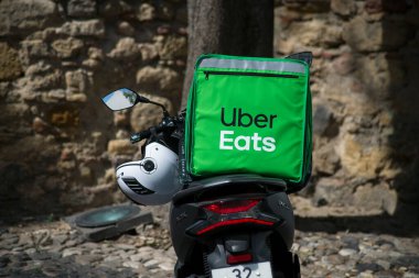Lizbon - Portekiz - 30 Eylül 2020 - Yeşil Uber yolda park etmiş scooter 'da teslimat çantası yiyor