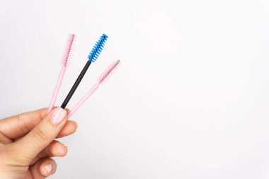 Kız ana kirpik uzantısı için beyaz arka planda az sayıda renkli kirpik fırçası.