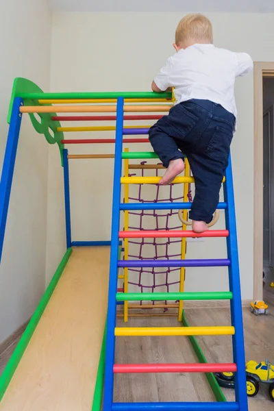 Boy play in the wooden sports complex with a slide in home childrens.