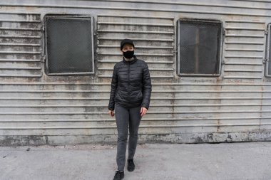 Salgın sırasında gri arka planda siyah maskeli bir kadın..