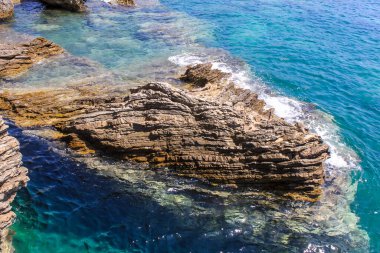 Denizin ortasındaki ya da okyanusundaki büyük kayalar. Büyük mavi su dalgaları bir taşın üzerinde kırılıyor..