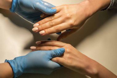 Eldivenli manikürcü müşterilerin elini tutuyor. Güzellik tedavisi konsepti. Salon manikür kursları. 