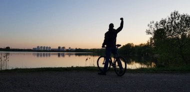 Gölün kıyısındaki parkta bir bisikletçi güzel bir manzaranın tadını çıkarıyor..