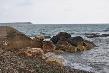 Sahili deniz dalgalarından korumak için dev taşlardan oluşan bir setten gelen dalgalı su.
