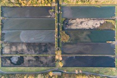 Demir fabrikalarından oluşan soyut sansasyon tankı, kazıcı çalışıyor, Dabrowa Gornicza Silesia Polonya 'daki su arıtma tesisi hava aracı görüntüsü