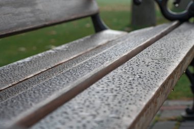 Bulanık yeşil zeminde yağmurdan sonra su damlayan kahverengi ahşap İngiliz anahtarı.