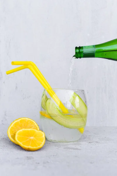 Pouring Soda Lemonade Bottle Cucumber Slices Lemon Wedges Straws Grey — Stock Photo, Image