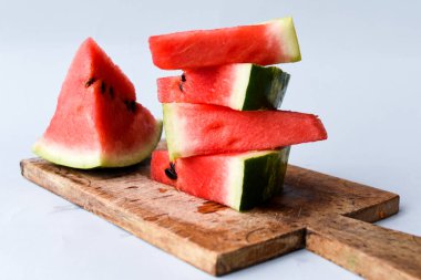 Kesme tahtasında dilimlenmiş karpuz. Gri bir zeminde karpuz suyu.