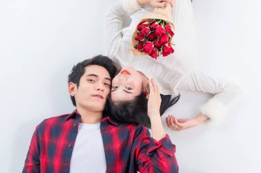 Mutlu genç çiftin üstte kameraya bakıp yerde yatarken gülümsediği görülüyor