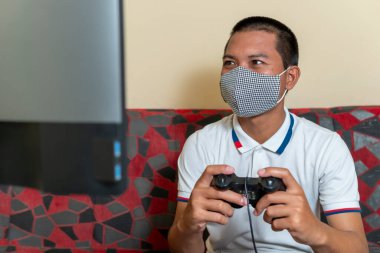 Erkekler evde tıbbi koruyucu maske takıp oyun oynuyorlar. Covid-19 virüsünün yayılma riskini azaltmak için, konsept Evde kalın ve evden uzak durun.