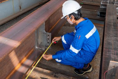 Teknisyenler boya için teslimattan önce çelik yapının doğruluğunu ölçmek için mezura kullanıyorlar..