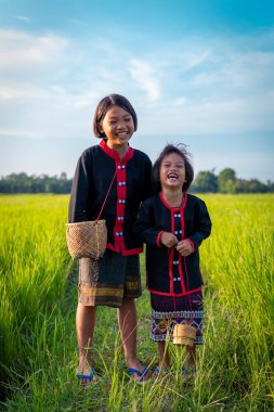 Yerel geleneklere göre giyinmiş iki Asyalı genç kız yeşil pirinç tarlalarının ortasında neşeli ifadeler ve gülücüklerle dikiliyorlar..