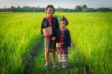 Yerel geleneklere göre giyinmiş iki Asyalı genç kız yeşil pirinç tarlalarının ortasında neşeli ifadeler ve gülücüklerle dikiliyorlar..
