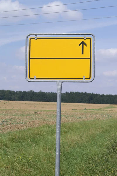 Yellow road sign with direction indicator on forest background