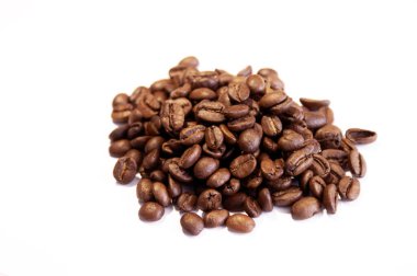 Beyaz arka planda bir sürü kavrulmuş kahve çekirdeği.