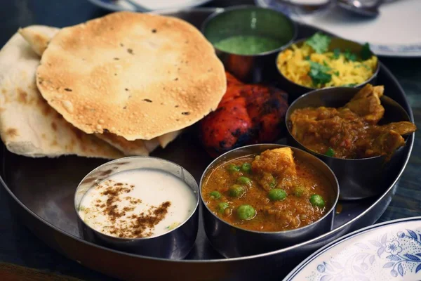 Assorted Indian food set in tray for dinner, tanduri chicken, naan bread, yoghurt, traditional curry, roti